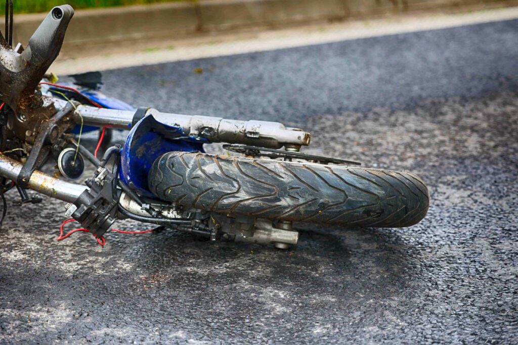 Damaged motorcycle lying on asphalt after road accident highlighting crash impact and personal injury risk