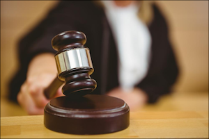 Judge’s Hand Holding a Gavel near a Sounding Block in a Court Room Judge About to Gavel on Sounding Block