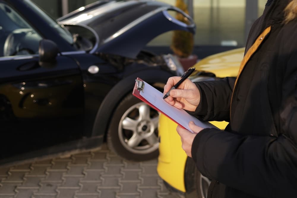 A woman records a car accident involving a black car and a yellow car.