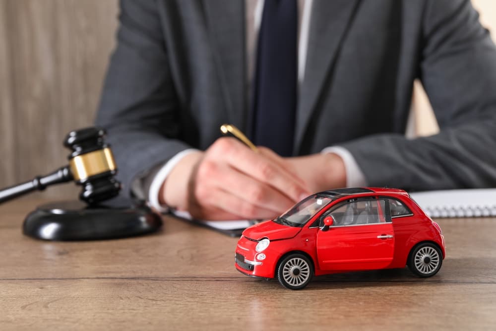 Auto accident law concept: A lawyer working at a wooden table indoors, with focus on a car accident case.