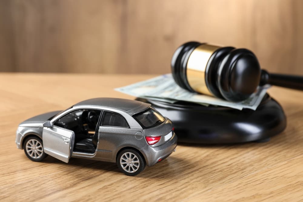 Close-up of a gavel, money, and a car model on a wooden background.