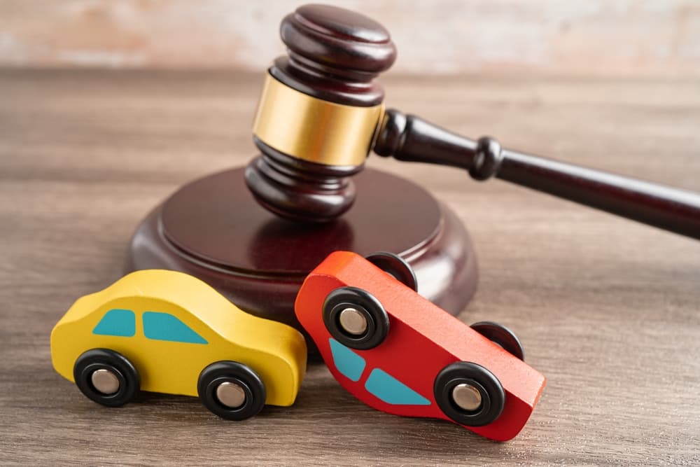 Judge's gavel with a car accident scene, representing an insurance claim, coverage dispute, or lawsuit in a court case.