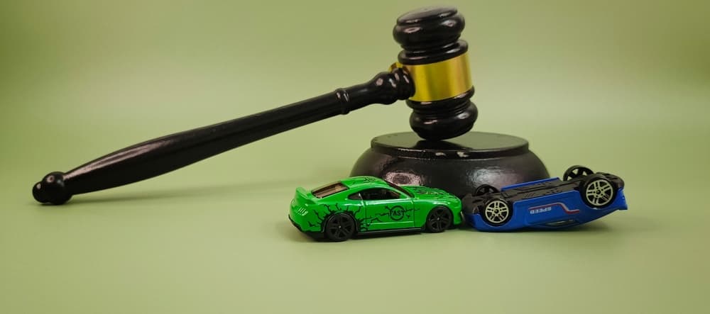 Car model and judge’s gavel on a table—symbolizing vehicle accident insurance, legal settlements, traffic lawsuits, and judicial decisions in automotive cases.