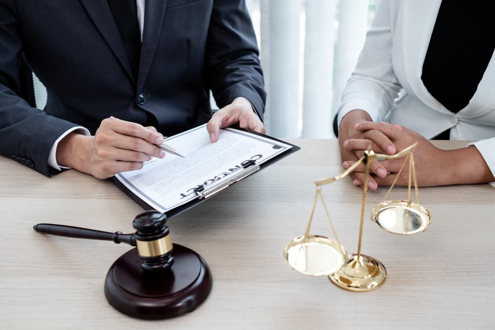 A male lawyer or judge advising clients on judicial justice and prosecution, with scales of justice, a judge's gavel, and legal documents—representing the concept of legal services.