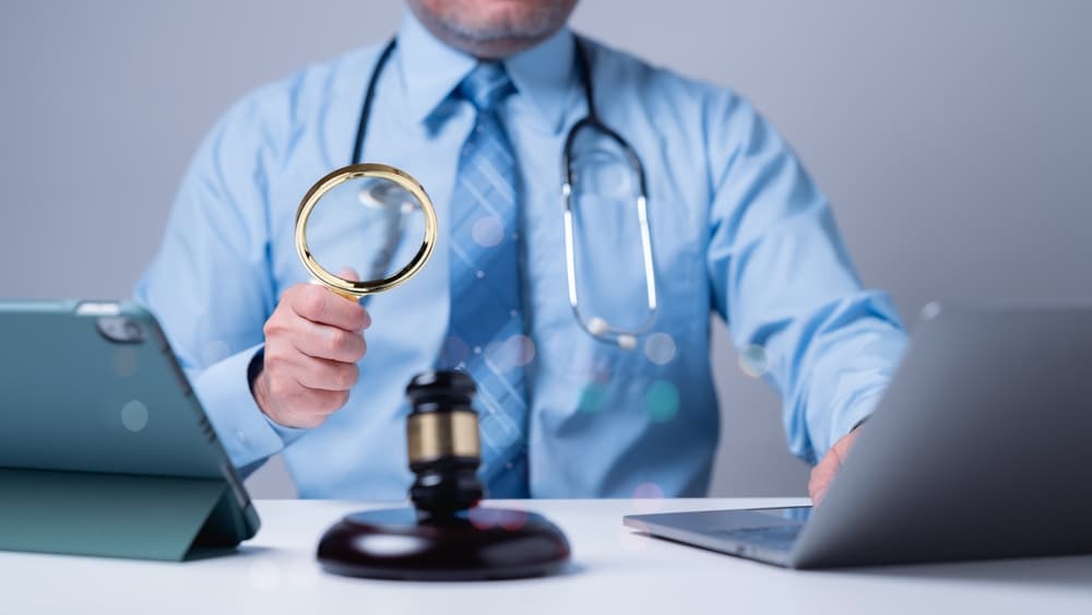 A medical professional examines documents with a magnifying glass, combining healthcare and legal analysis to ensure compliance and quality. Technology supports the investigation of medical practices.