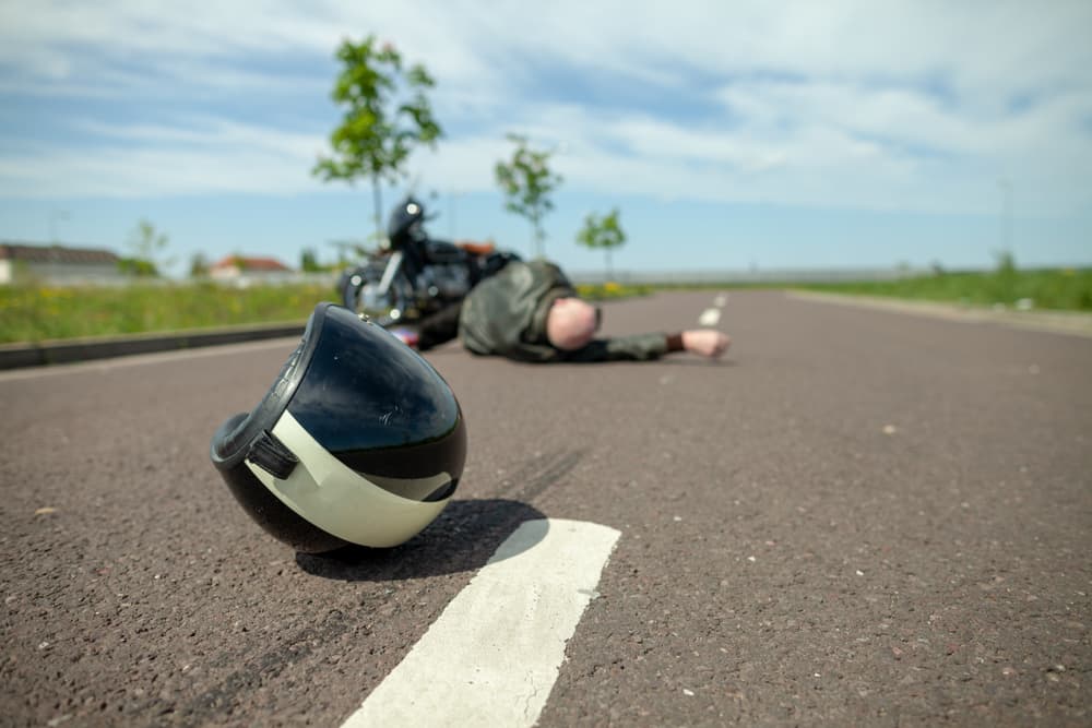 A biker's helmet lies on the street near the scene of a motorcycle accident.