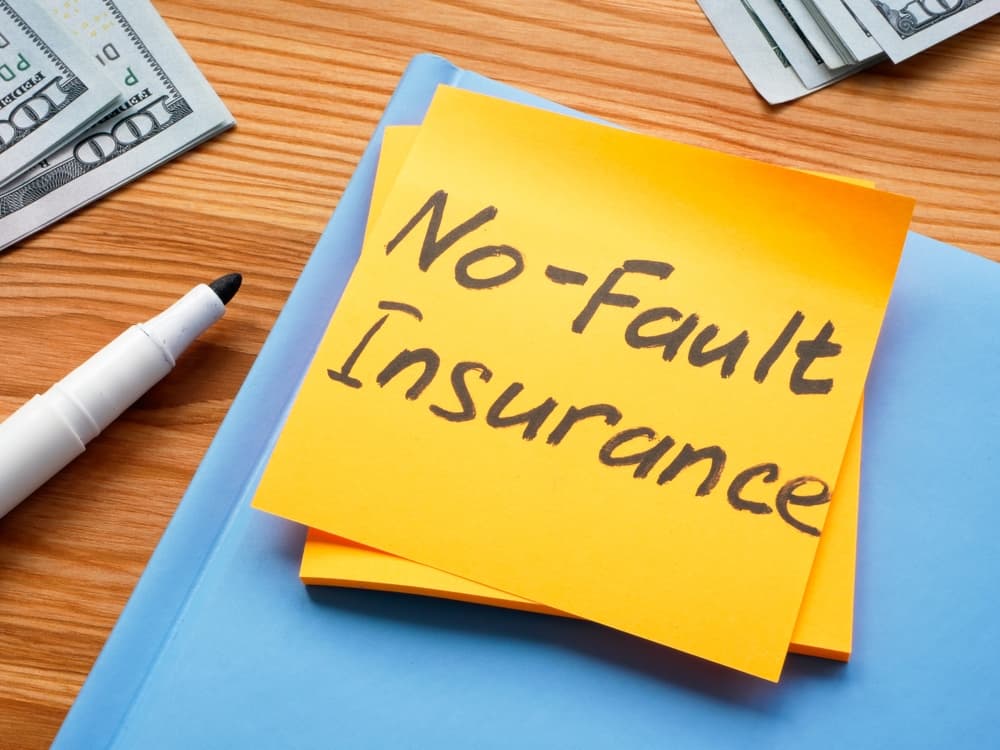 A sticker with the memo 'No-Fault Insurance' placed next to a notepad.