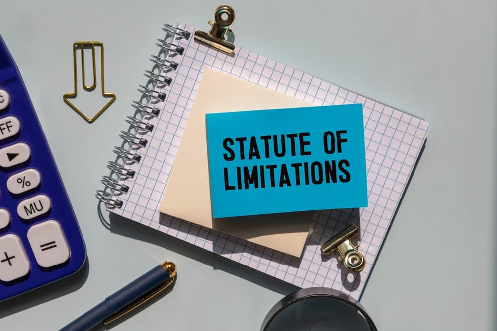 Law and justice concept: A notebook with the inscription 'STATUTE OF LIMITATIONS,' accompanied by a calculator and a pen.