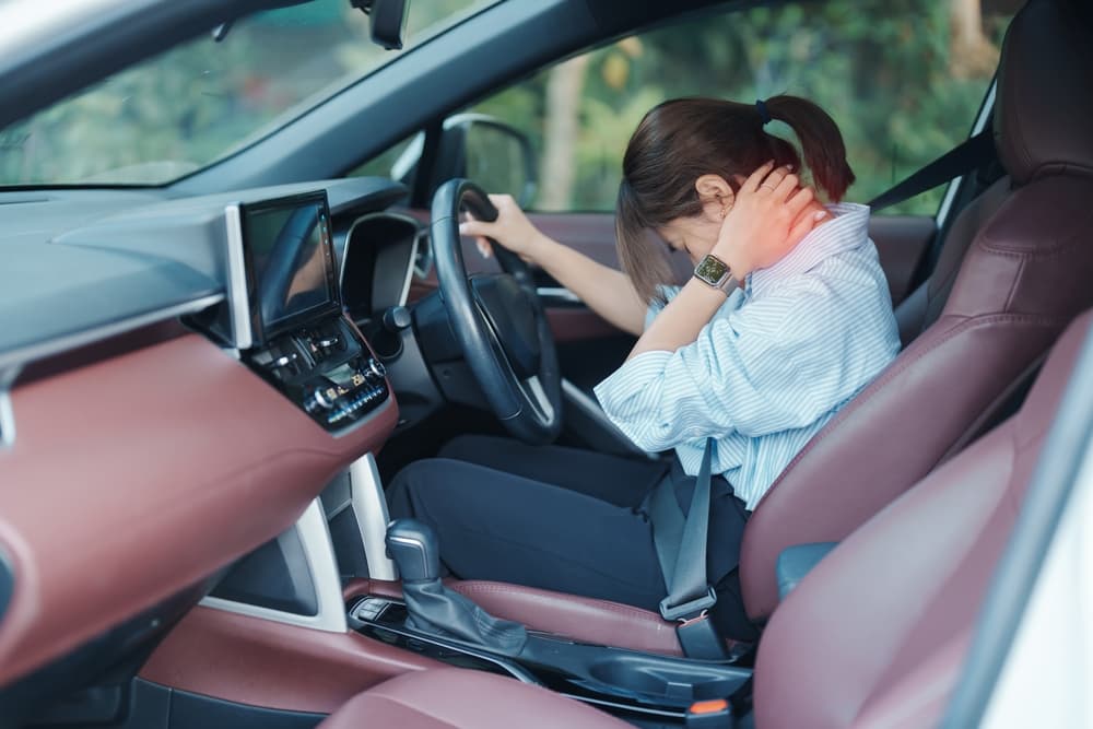 A woman experiences shoulder and neck sprain after driving for an extended period, suffering from muscle pain. The scene highlights issues such as shoulder ache, scapular pain, office syndrome, and poor ergonomics.