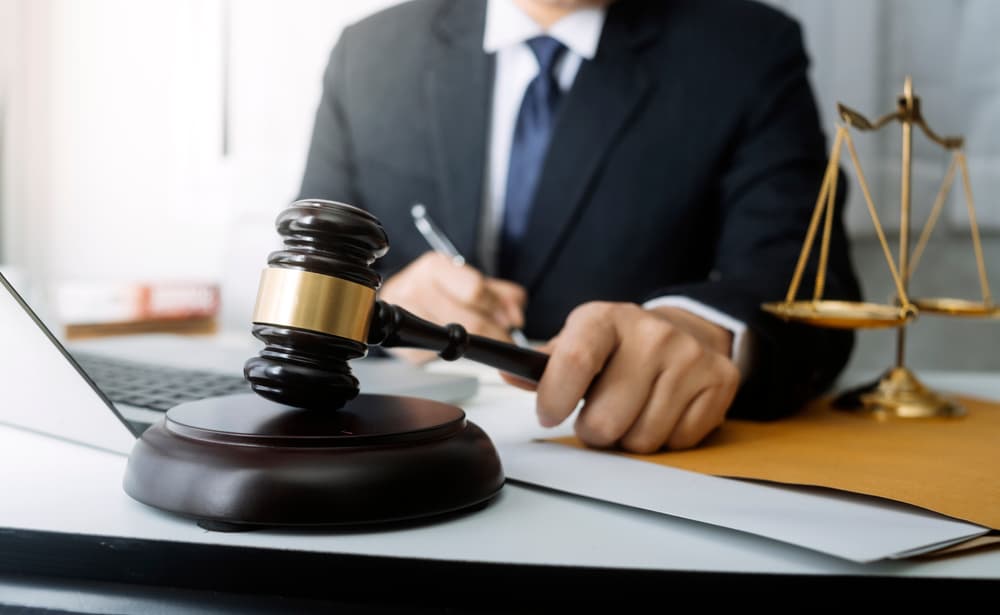 A lawyer reviews documents in an office, with a brass scale on the desk symbolizing justice—conveying the core of legal services, counsel, and law, all set against a film grain backdrop.