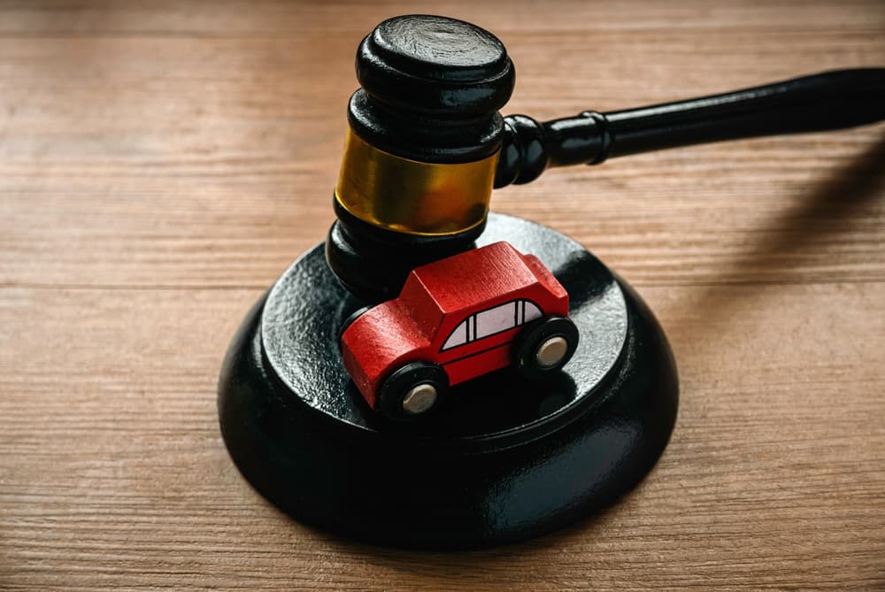 A gavel next to a toy car symbolizes the concept of a car auction, accident lawsuit, or insurance claim, representing legal and financial decisions involving vehicles.