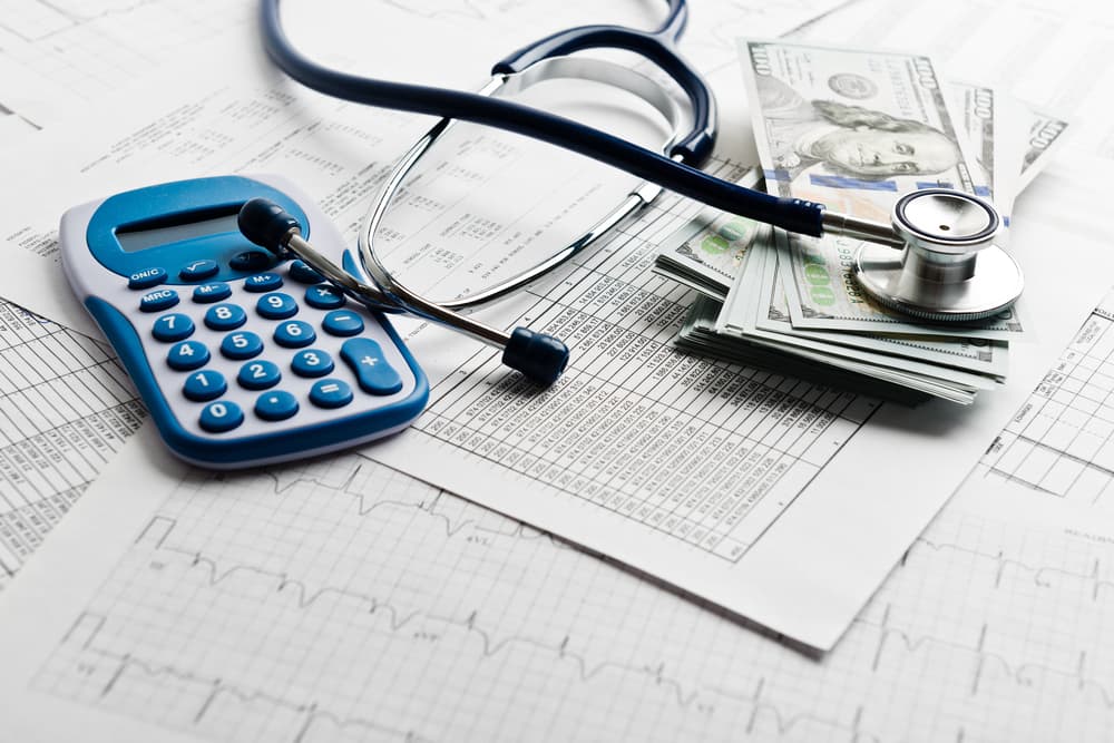 A stethoscope and calculator placed together symbolize health care costs, representing the financial aspects of medical treatment and health insurance.