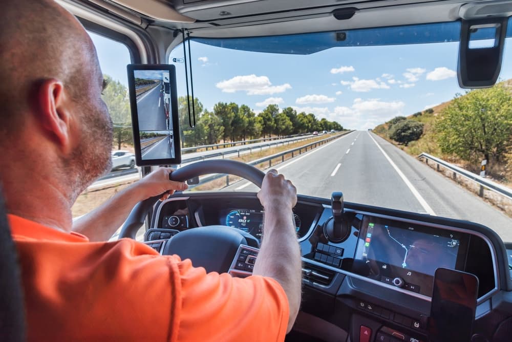 A truck driver focuses intently while driving down a straight highway.