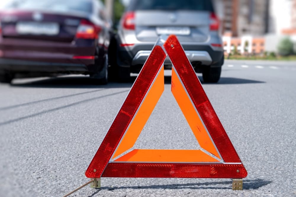 A collision between two vehicles with a road warning triangle sign in focus.
