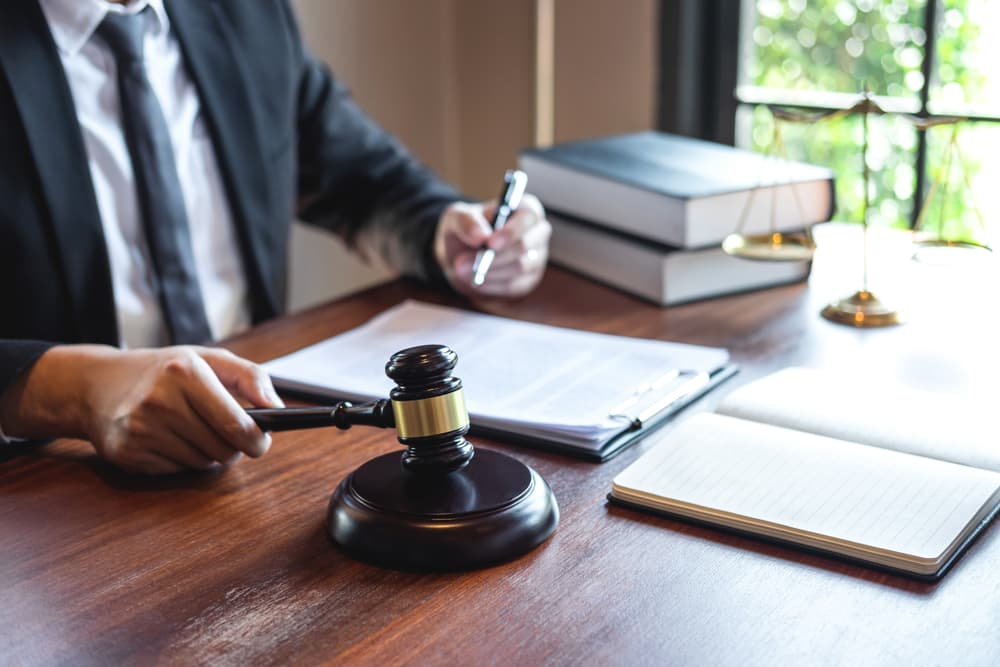 A professional male lawyer or legal counselor reviews a case contract document in his office, representing law, justice, and the role of an attorney in handling lawsuits.