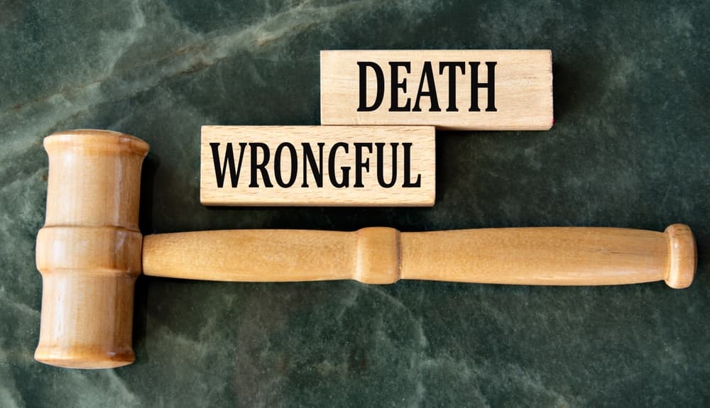‘WRONGFUL DEATH’ spelled out on wooden blocks against a green background, with a judge’s gavel symbolizing legal proceedings.