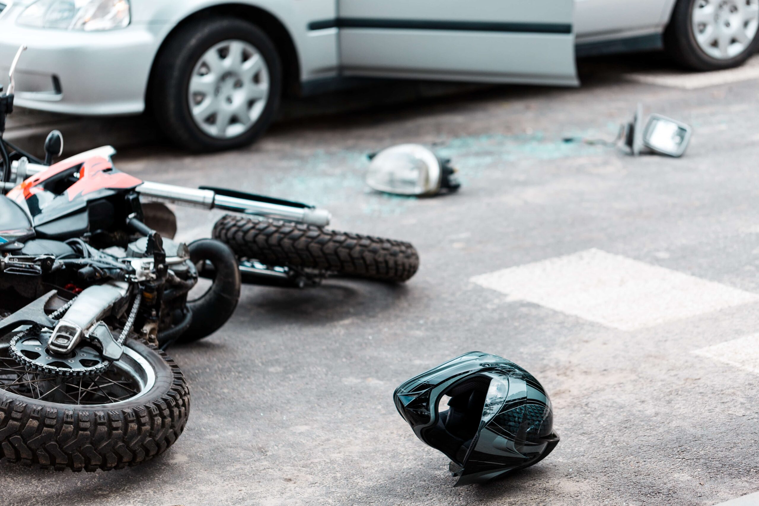 crashed motorcycle lying on the street next to a car