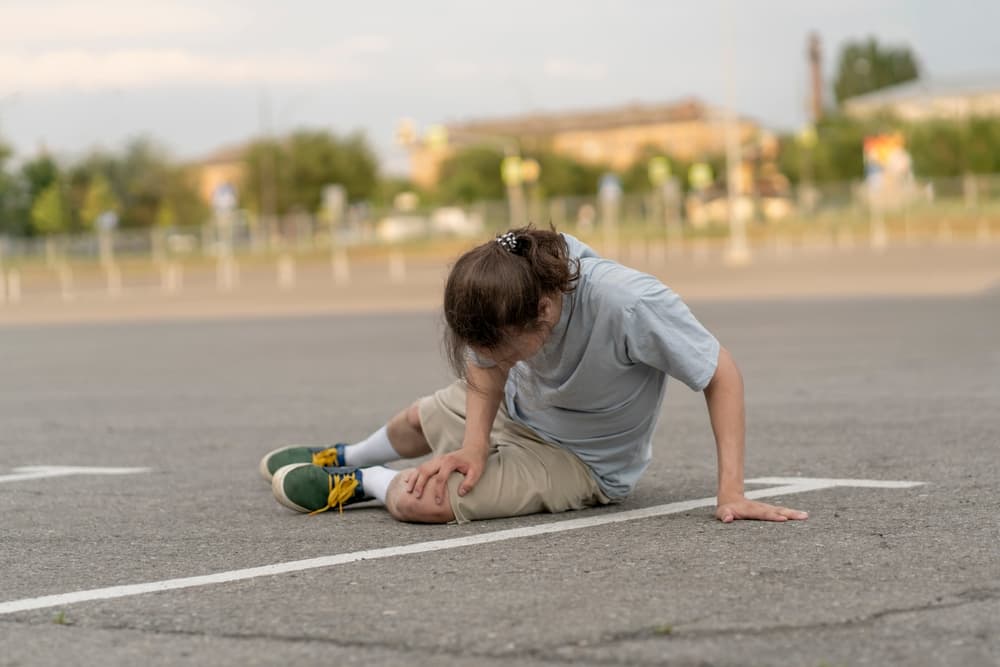 A person walking down the street trips and falls to the ground.