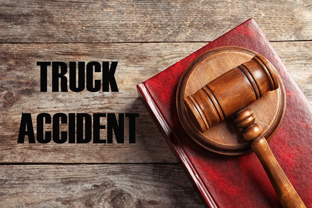 Truck accident law concept. Judge's gavel and legal book on a wooden table, viewed from above.