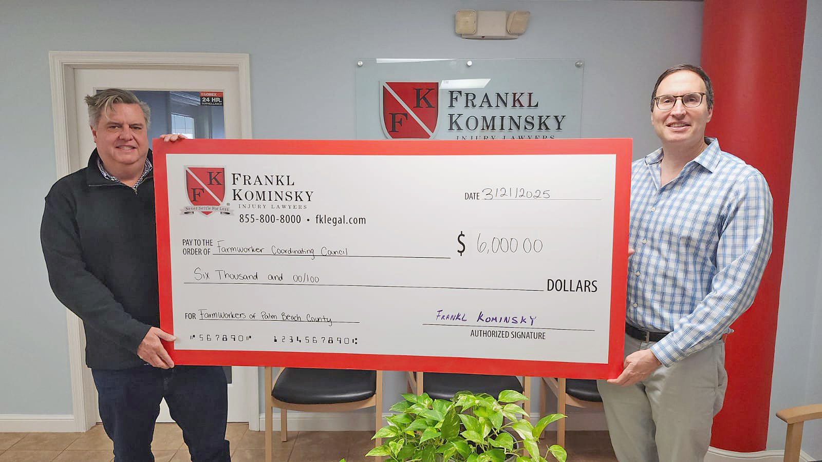Two men stand holding a large ceremonial check for \$6,000 made out to the Townworker Coordinating Council from Frankl Kominsky Injury Lawyers.