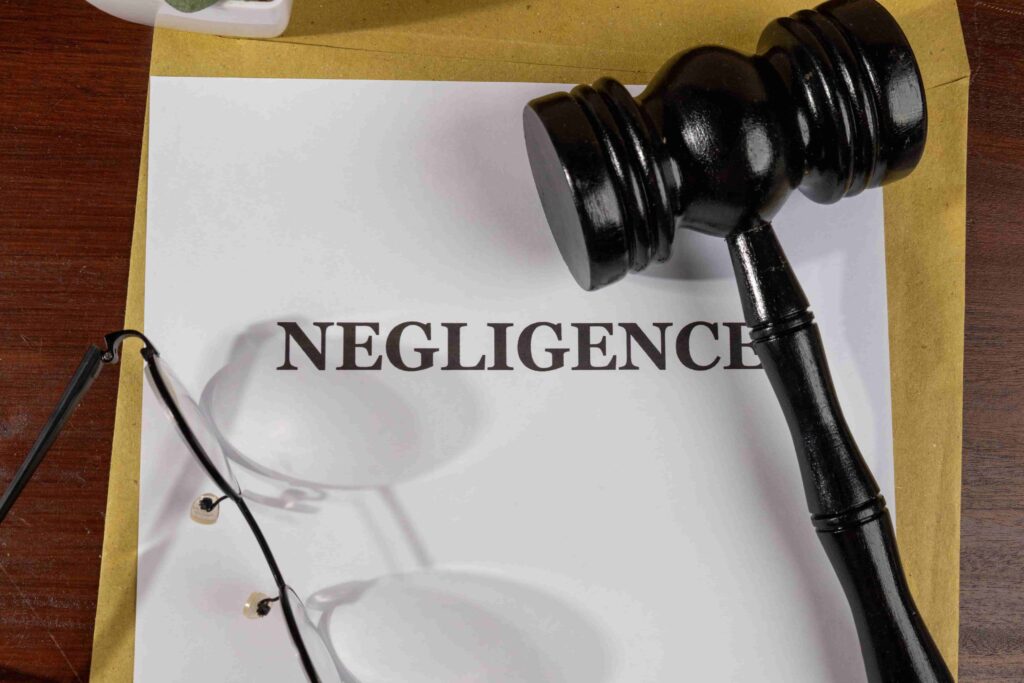 Negligence legal concept with judge’s gavel, legal document, and eyeglasses on desk.