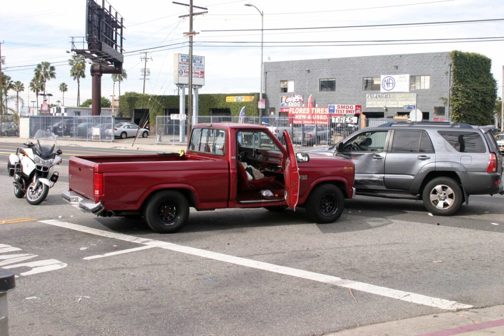 Pickup truck and SUV collision at intersection with police motorcycle on scene during traffic accident investigation