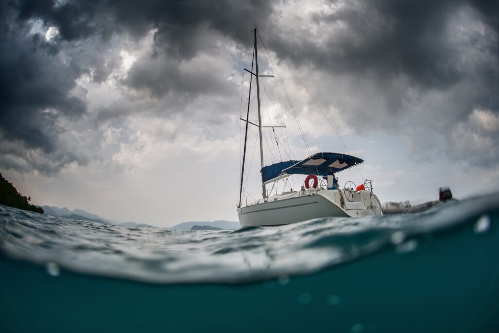 Sailboat on open water under dark storm clouds, symbolizing boating safety risks and accident danger
