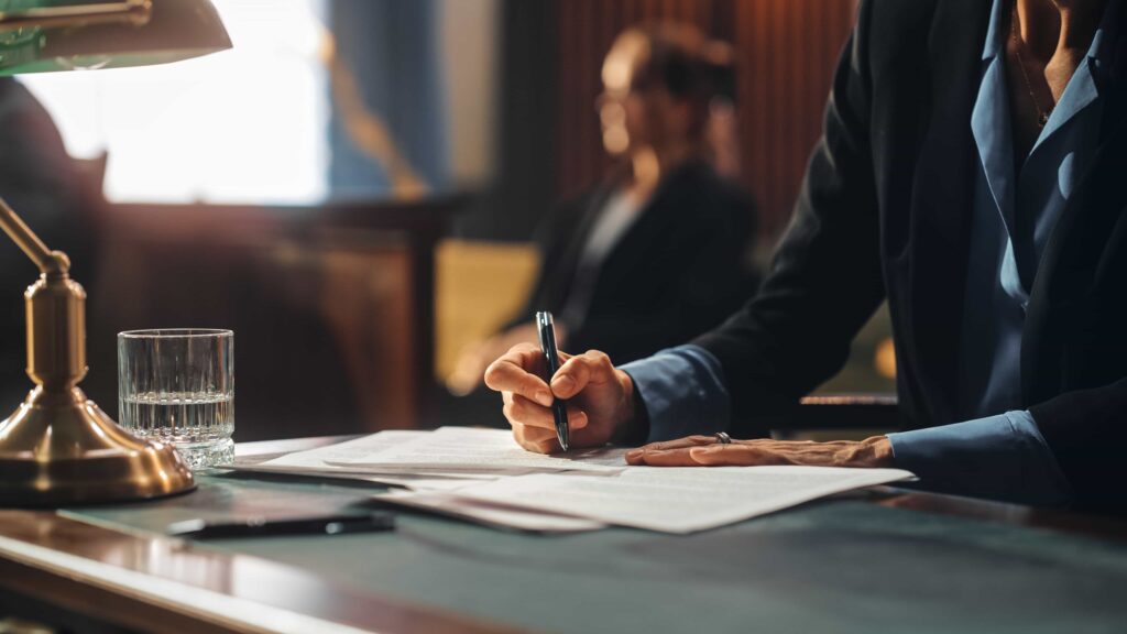 Lawyer writing legal documents at courtroom desk during trial proceedings.