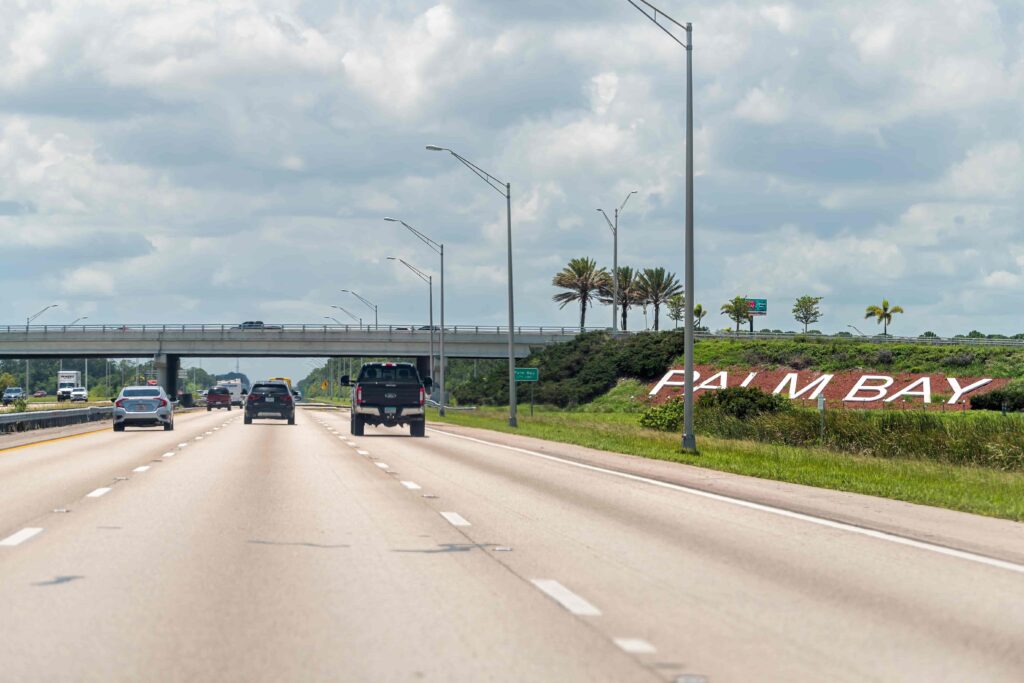 Highway view entering Palm Bay, Florida with cars driving under an overpass and city welcome sign on the roadside. Highway view entering Palm Bay, Florida with cars driving under an overpass and city welcome sign on the roadside.