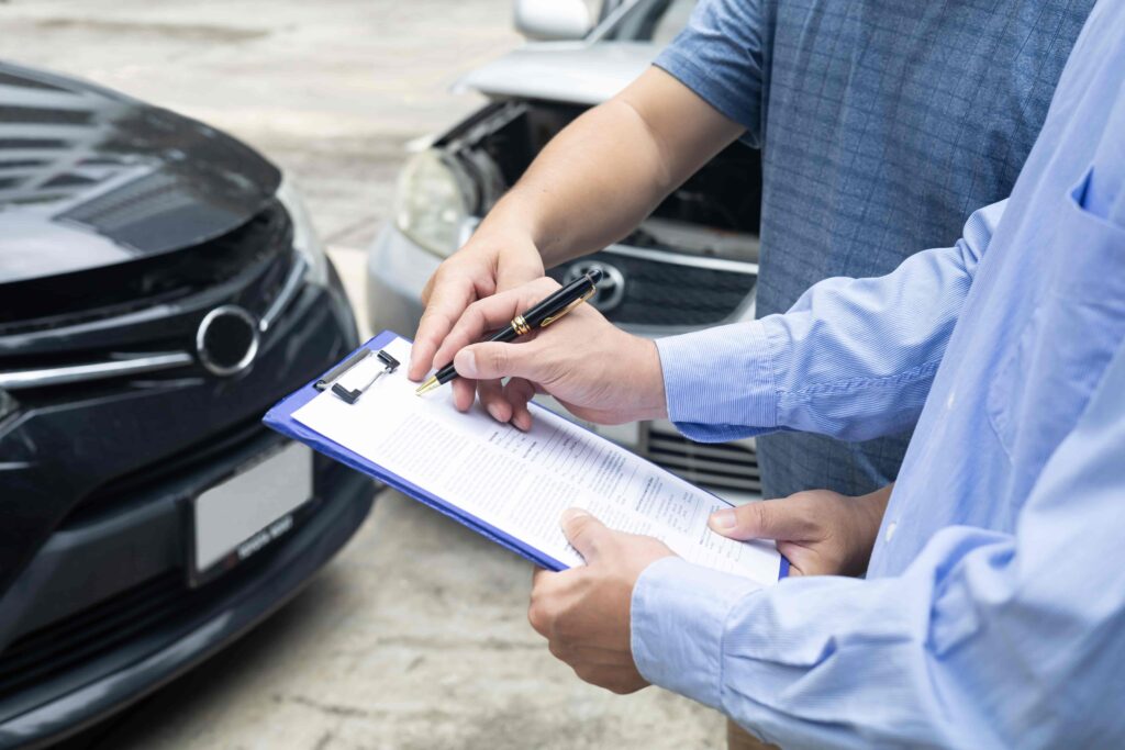 Insurance agent and driver reviewing accident report after car crash for personal injury and auto claim settlement Insurance agent and driver reviewing accident report after car crash for personal injury and auto claim settlement