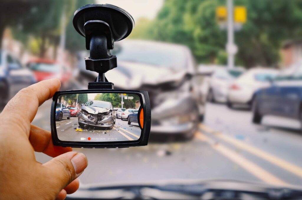 Dash cam recording footage of a car accident with vehicle damage on a busy street. Dash cam recording footage of a car accident with vehicle damage on a busy street.