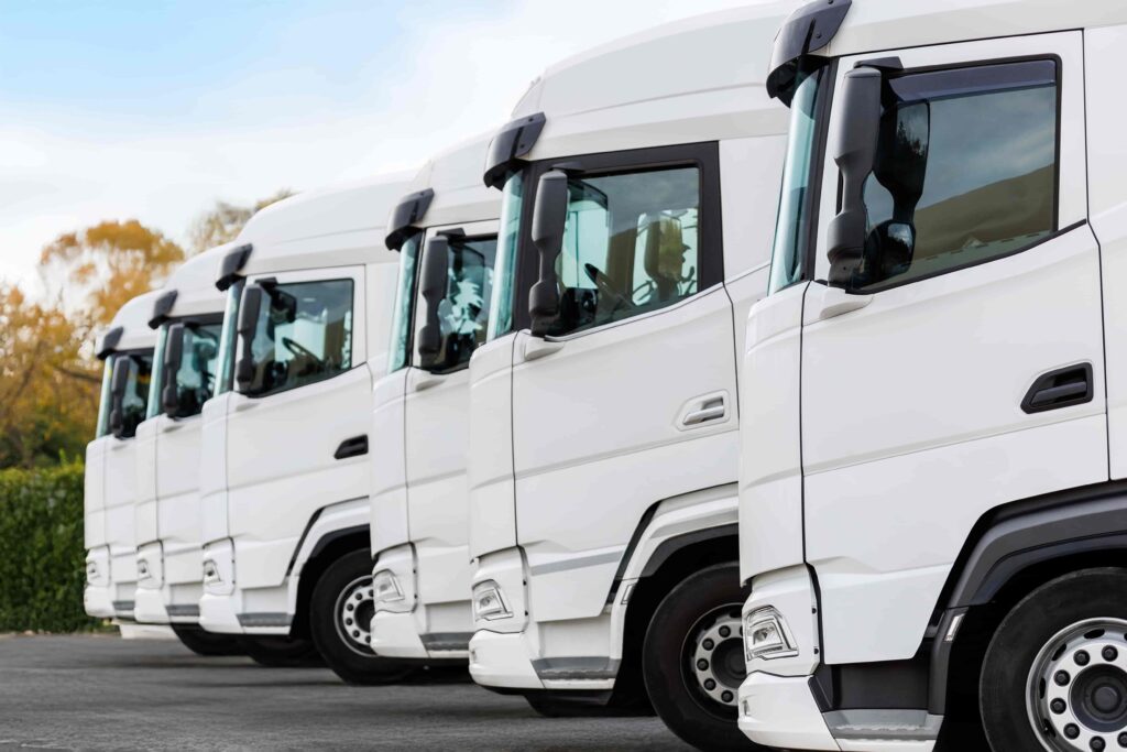 Fleet of white semi-trucks parked in a row at a transportation and logistics hub Fleet of white semi-trucks parked in a row at a transportation and logistics hub