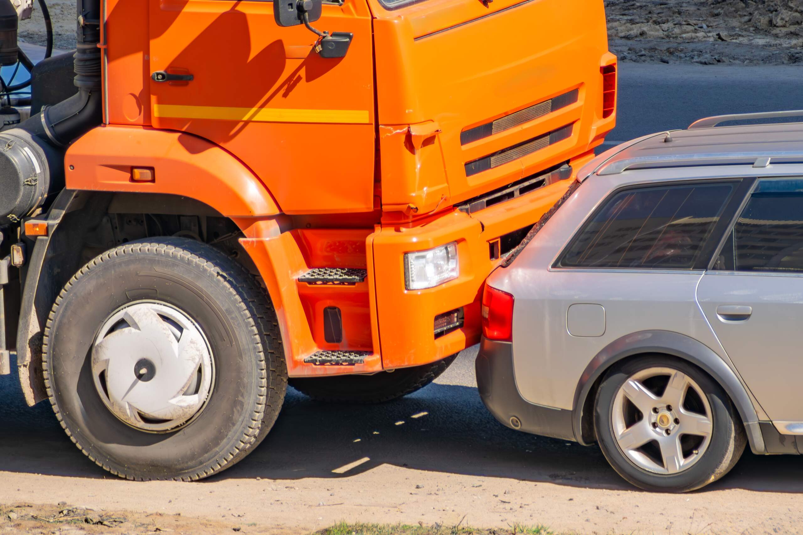 Close-up of a car crushed by a large truck in a Florida crash, highlighting injuries and losses recoverable in a truck accident lawsuit.