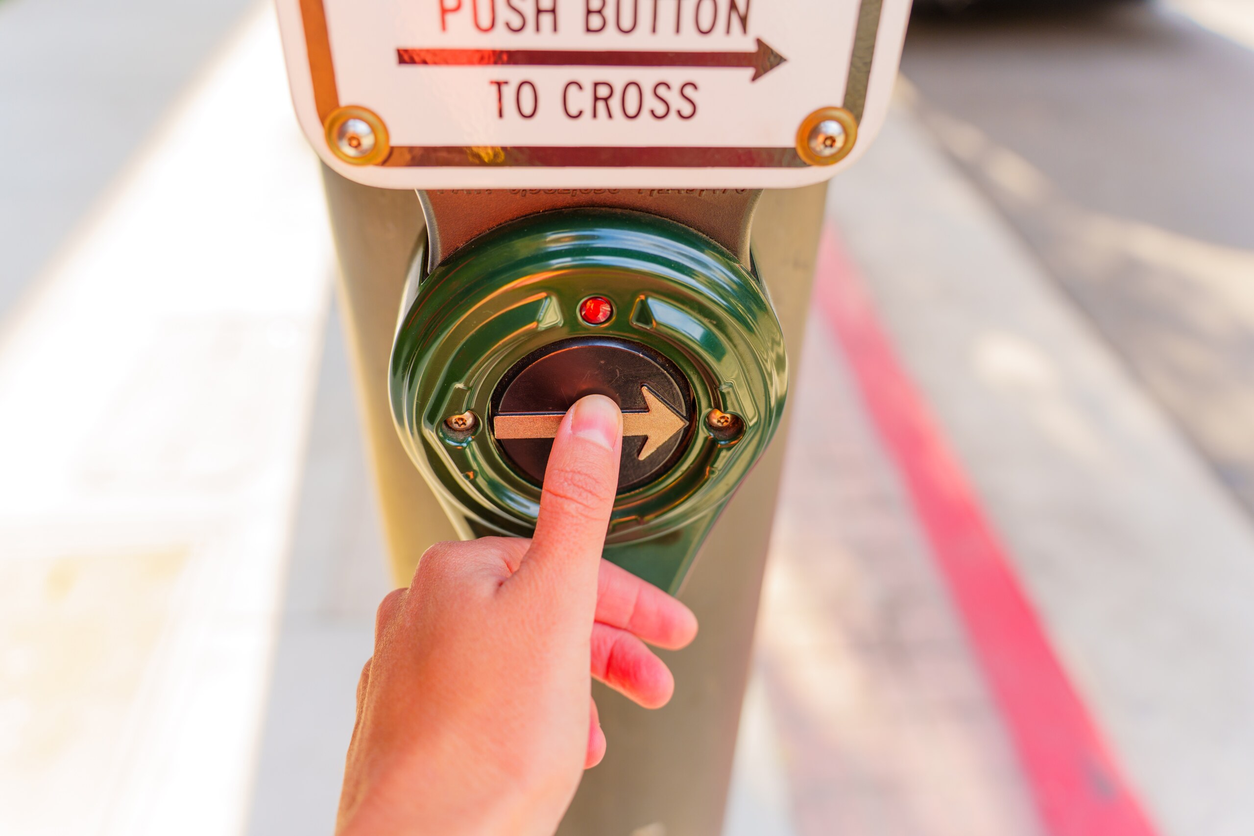 Pedestrian pressing crosswalk button at an intersection, highlighting right-of-way laws in Florida.