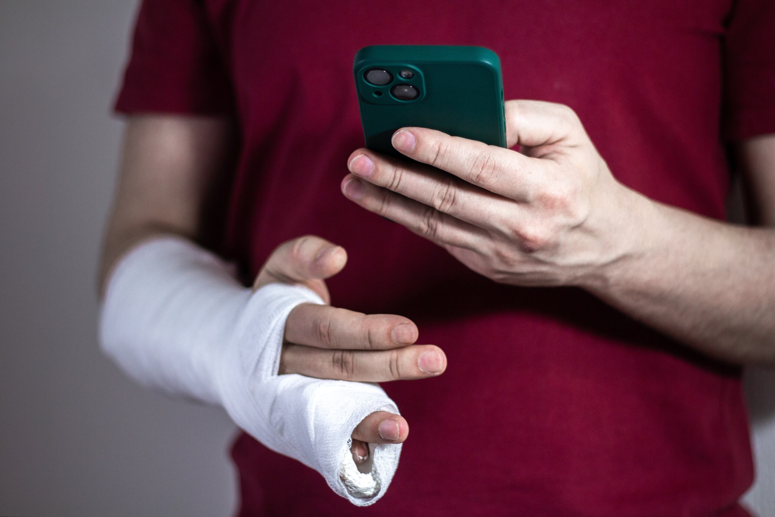 Injured driver with arm in cast using a phone after a Florida T-bone accident, highlighting fault and injury concerns.