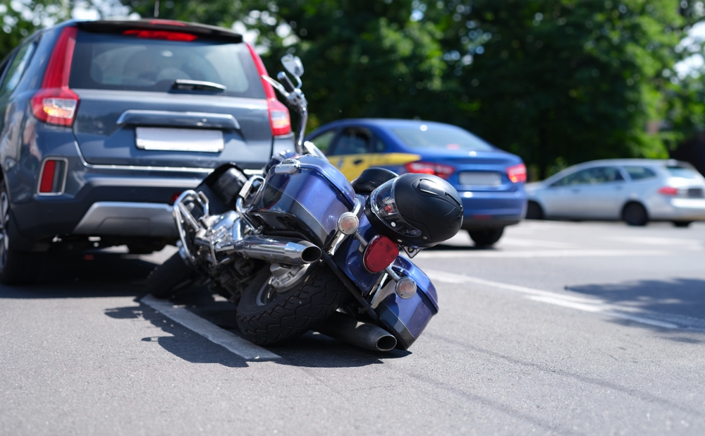 Blue motorcycle crushed under the rear of a white vehicle in Boca Raton representing a serious dooring motorcycle accident and the legal rights of injured riders under Florida law