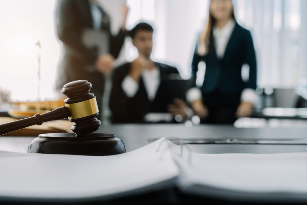 Boca Raton, FL motorbike accident lawyer arguing in court, with a judge and business individuals attentively listening in the background.