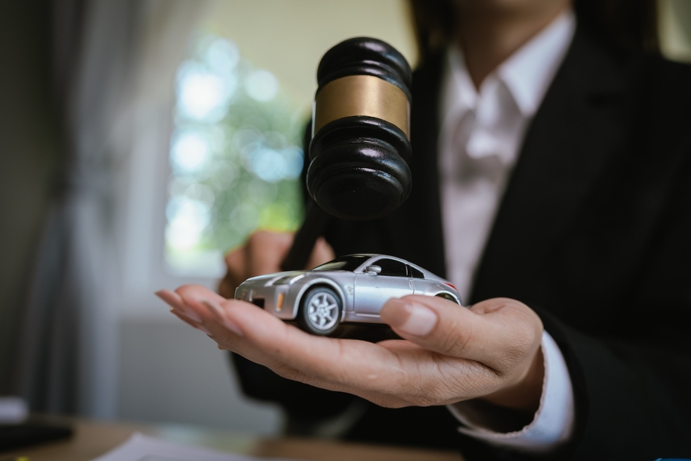 Boca Raton car accident attorney at Frankl Kominsky Injury Lawyers holding a gavel over a toy car representing legal action in a Florida car accident claim
