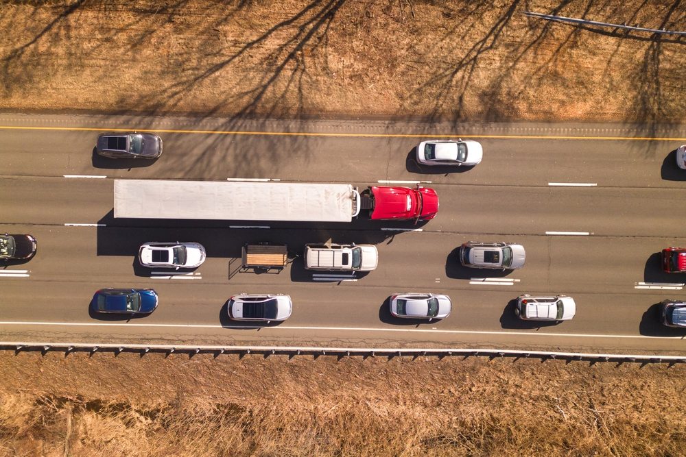 Aerial view of a commercial semi truck merging aggressively through highway traffic in Boca Raton illustrating the danger of truck accidents on Florida roads