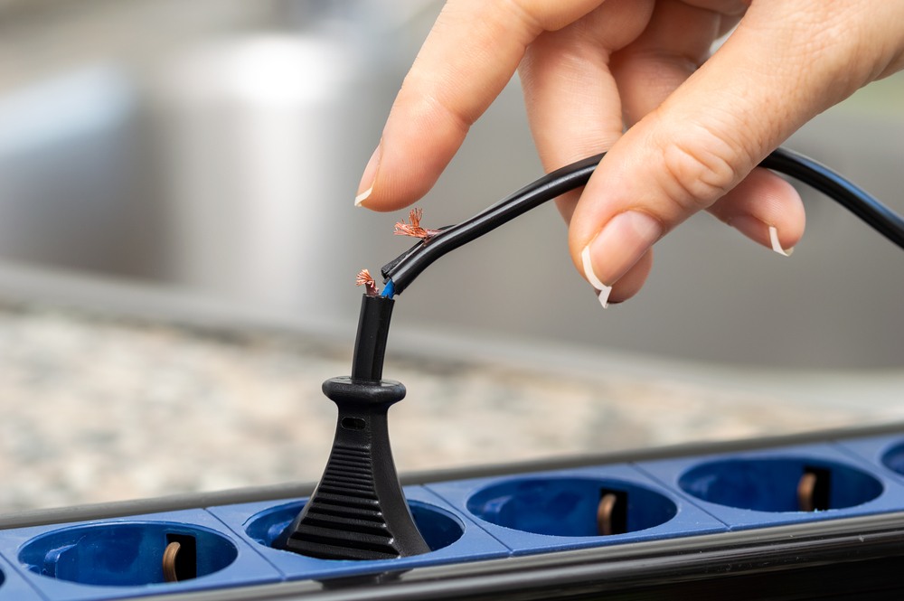 Frayed exposed wiring near a power strip, a common cause of electrocution accidents