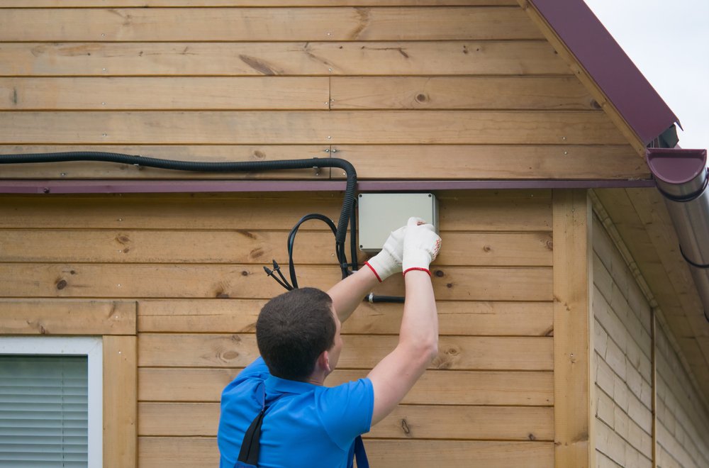 Worker installing electrical equipment on a building exterior