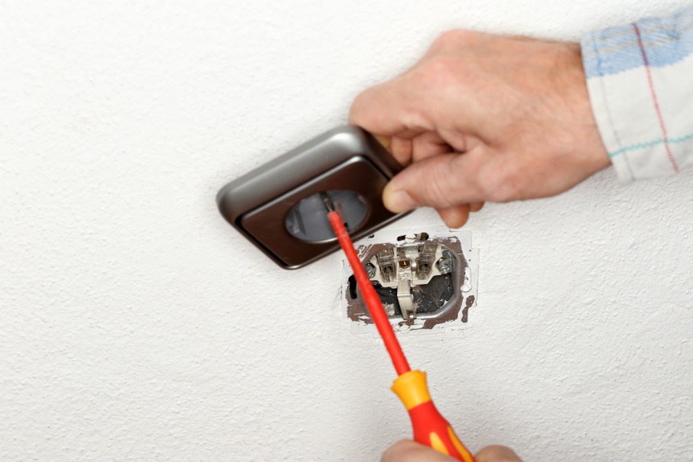 Electrician working on exposed wiring in an outlet
